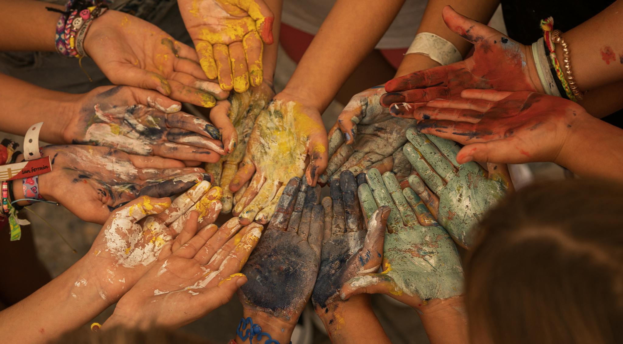 A close-up of a group showing painted hands in vibrant colors symbolizing unity and creativity.