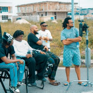 Group of men casually filming with equipment outside under construction area.