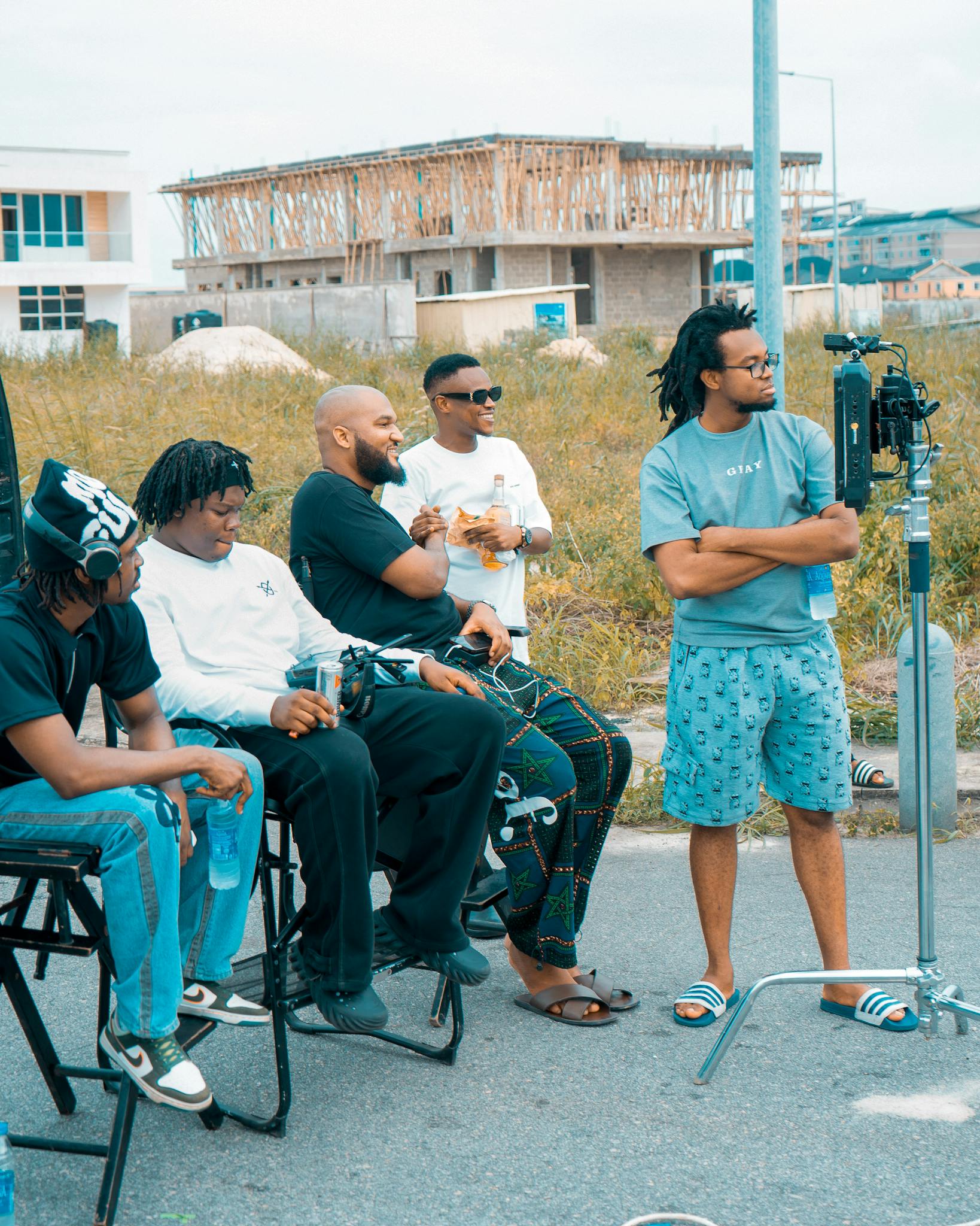 Group of men casually filming with equipment outside under construction area.