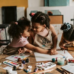 Three children engaged in an art activity, painting together with watercolors and brushes.