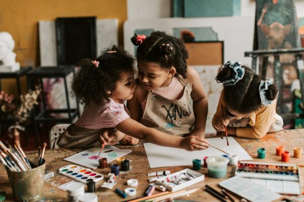 Three children engaged in an art activity, painting together with watercolors and brushes.