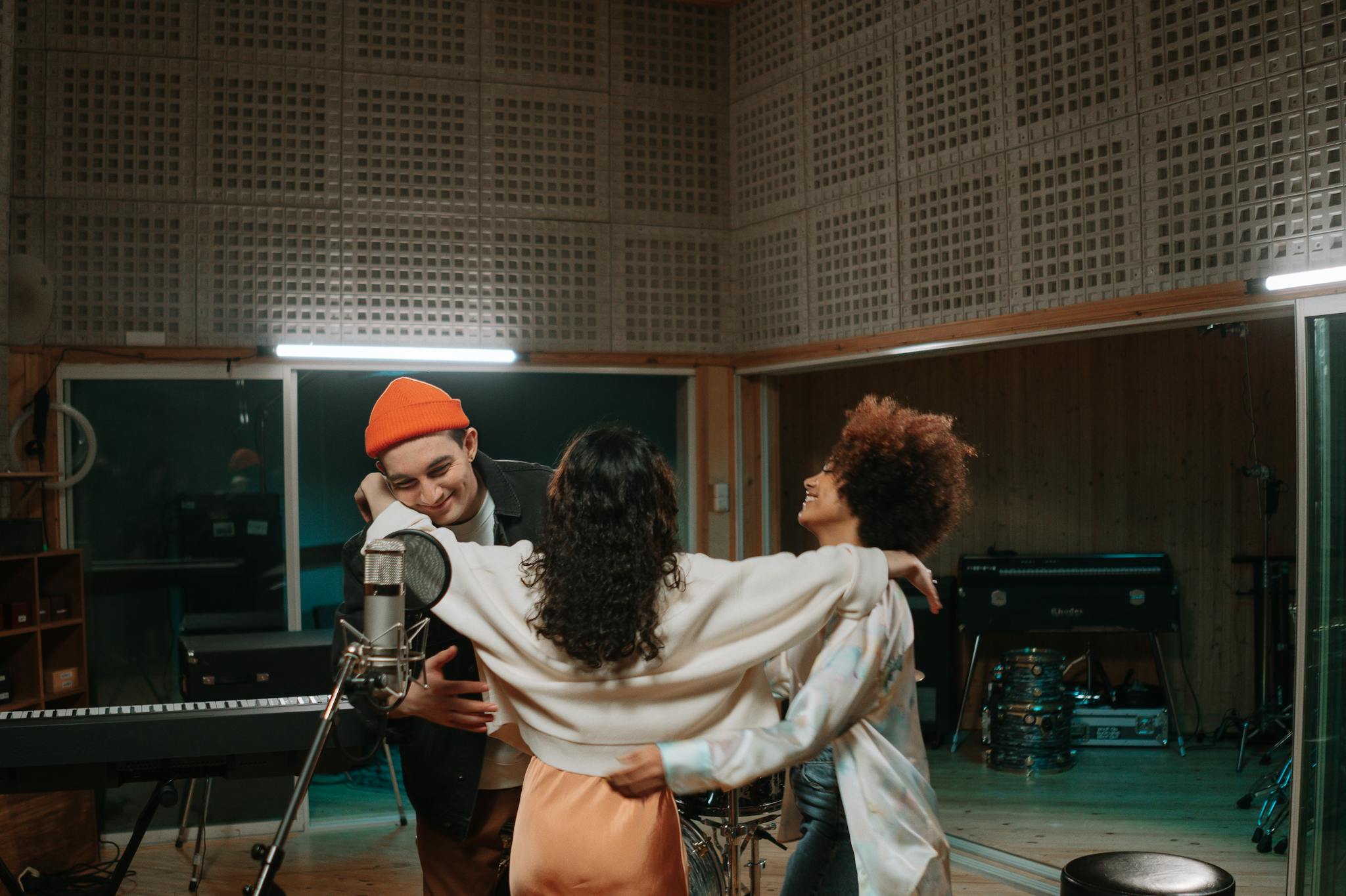 Three friends enjoying a joyful moment together in a music studio.